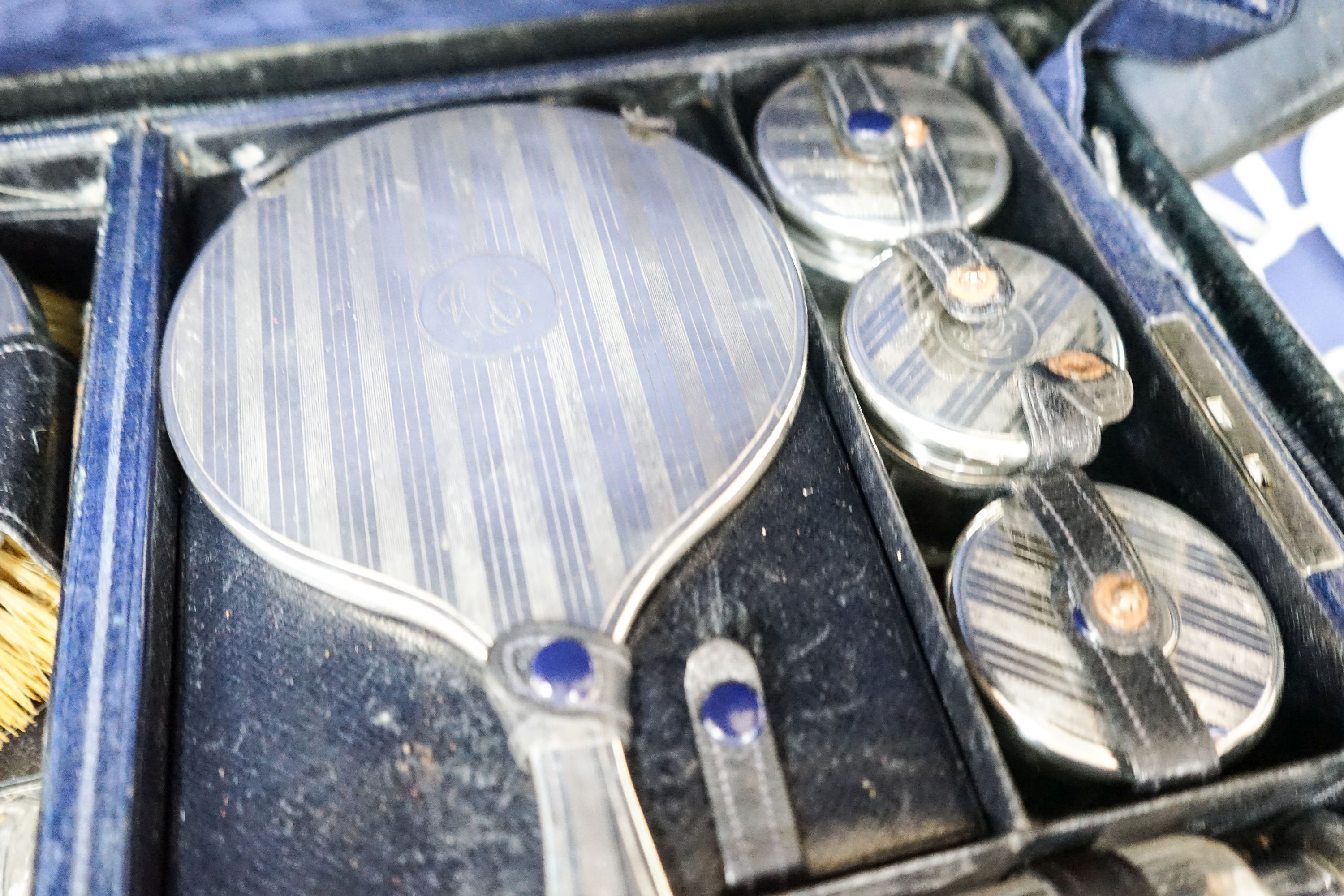 A George V traveling toilet case, fitted with fourteen silver mounted backed brushes, a mirror and toilet bottles etc. London, 19201/2.